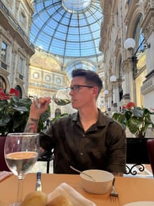 Steven with a glass of wine in a grand glass-roofed arcade